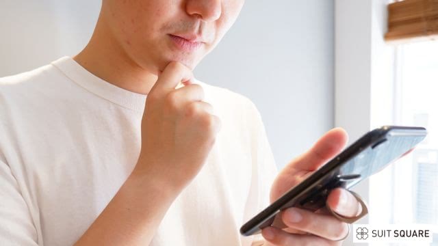 男性がスマートフォンで比較している